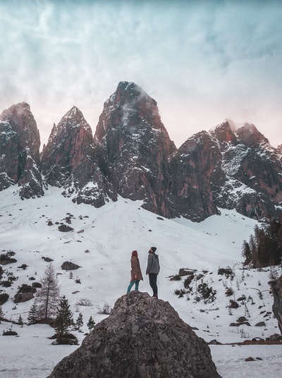 男人和女人站在与冰川山脉的一座山的距离在一天
